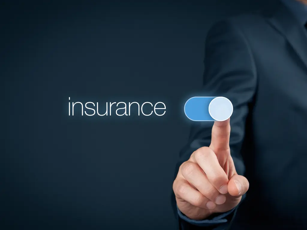 A person’s finger is pressing a blue on/off switch next to the word “insurance” on a dark background.