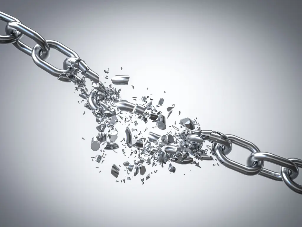 A metal chain breaking apart in the middle with fragments and pieces flying outward against a light gray background.