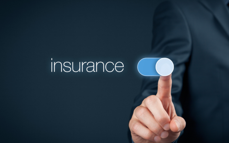 A person’s hand in a suit jacket is pressing a virtual switch labeled “insurance” against a dark background.