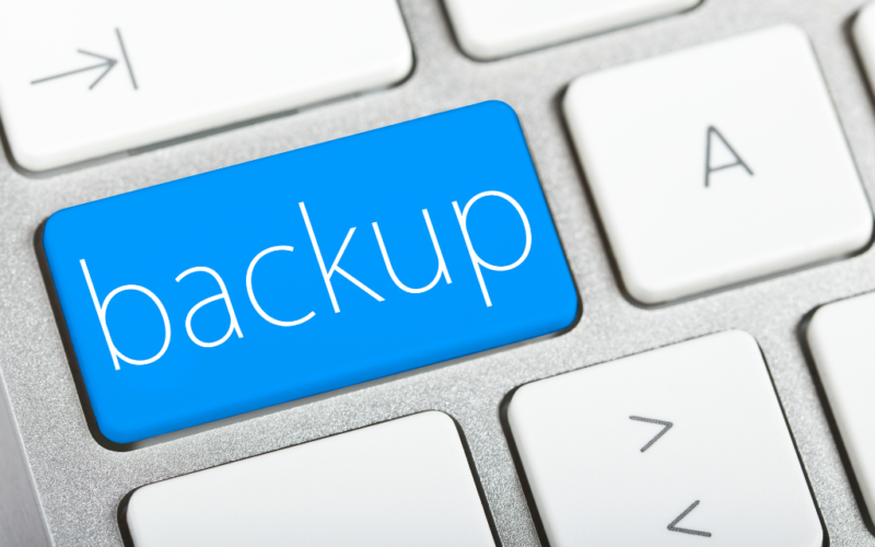 A close-up of a computer keyboard with a large blue key labeled "backup" in white letters, symbolizing data backup or security.